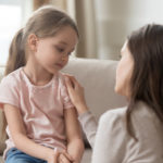 Mother comforting daughter in a home setting.