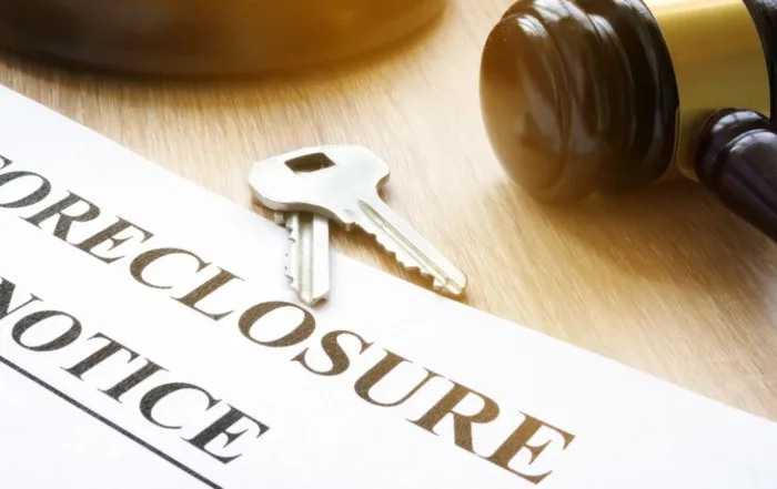 Foreclosure notice document next to house keys and a judge’s gavel, symbolizing the legal process of property repossession due to mortgage default.