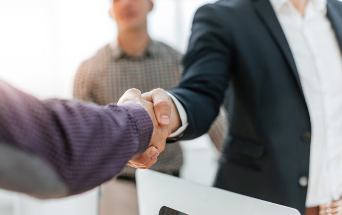 Close up of two men shaking hands in an office